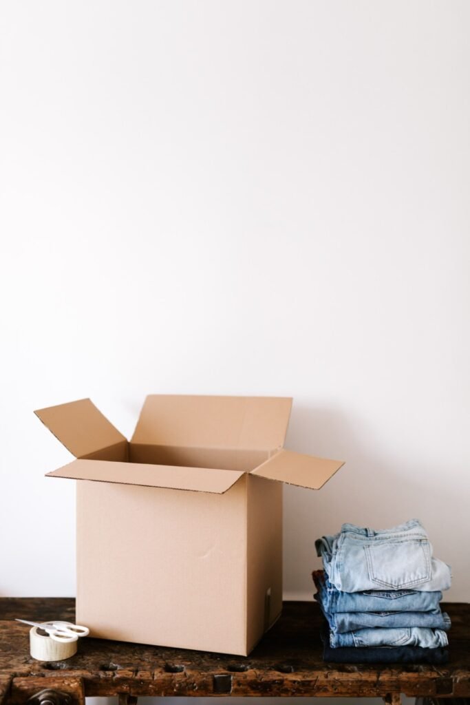Open carton and folded clothes prepared for a home move.