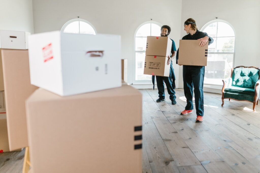 Two movers carrying cartons through a home during relocation in Dubai.