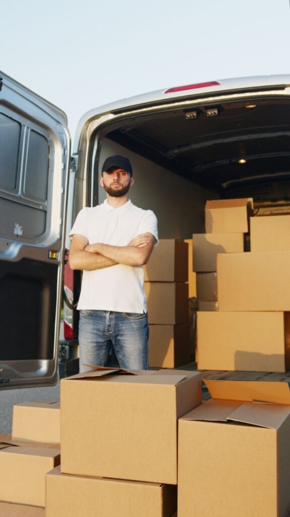 Mover beside household cartons in a loaded van.