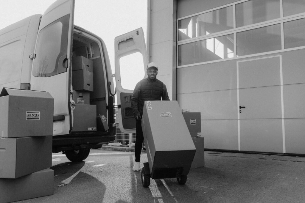 Mover wheeling a carton from a van during a relocation.
