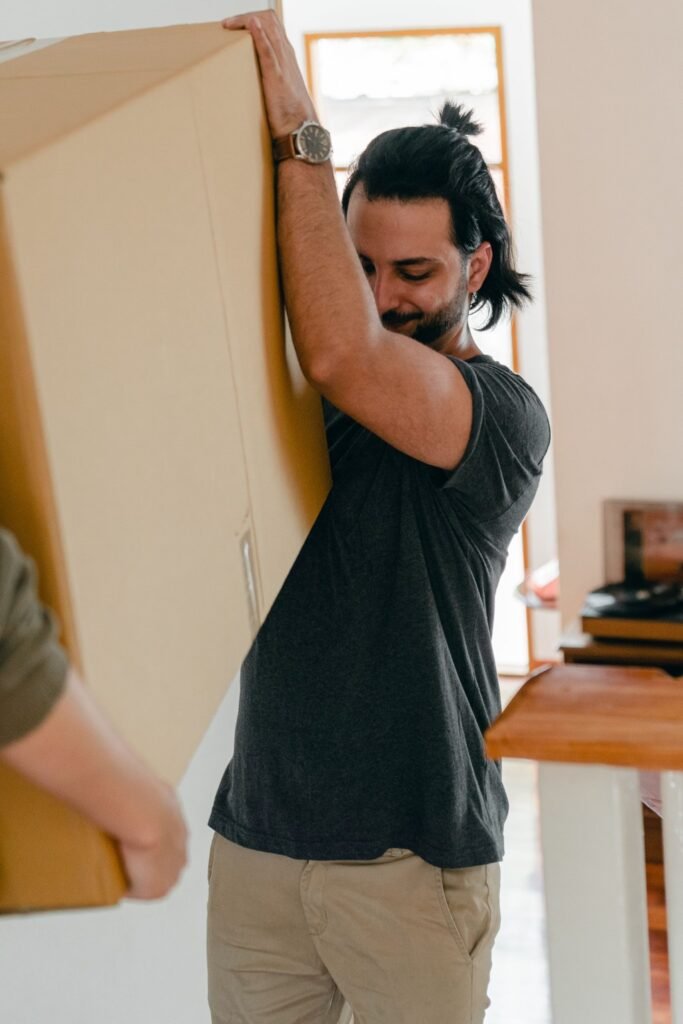 Mover carrying a large carton through a home during a Dubai move.