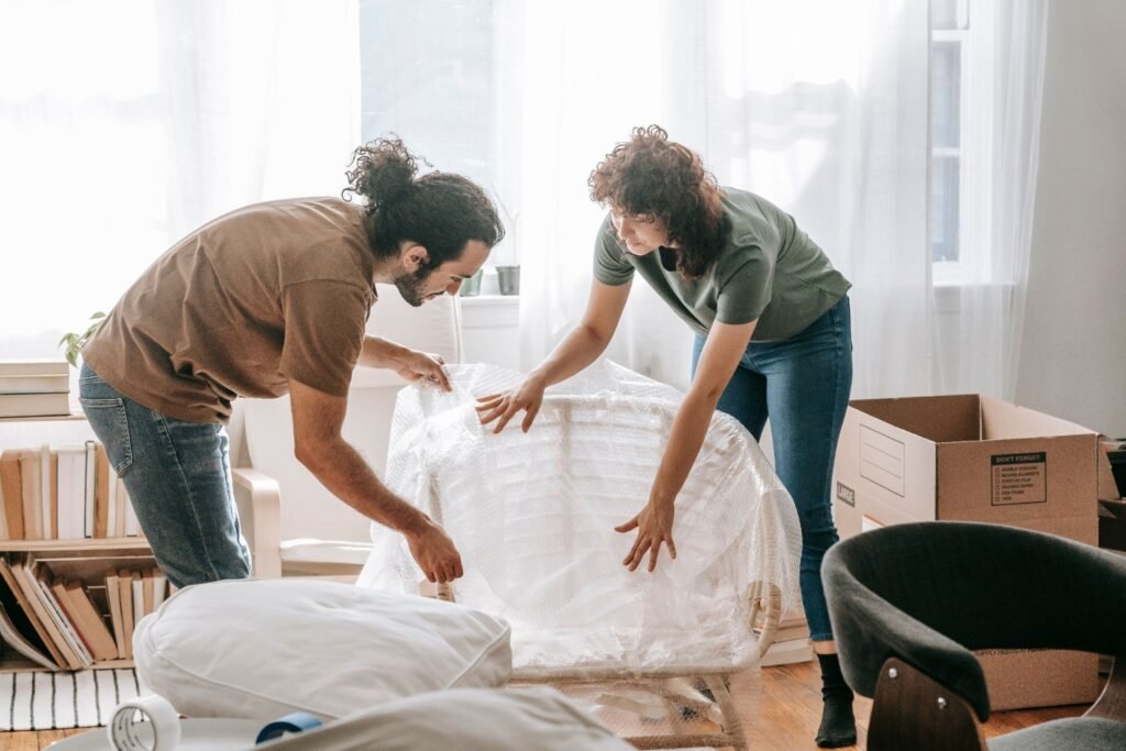 Two people wrapping furniture during a home move.